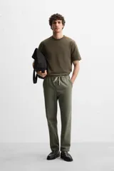 Pantalón de jogging color beige confeccionado en tejido de mezcla de algodón. Cuenta con cintura elástica ajustable con cordón, bolsillos frontales y traseros.