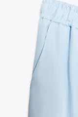 Pantalón celeste de tiro alto con cintura elástica, bolsillos delanteros y pierna ancha.