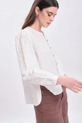 Blusa color crudo con textura, mangas largas abullonadas y cierre frontal con botones.