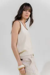 Musculosa de punto color salmón con cuello y sisas ribeteadas en rojo.