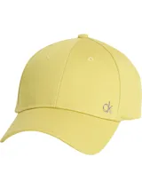 Gorra de béisbol color amarillo pálido, confeccionada en sarga de algodón orgánico, con visera curva y cierre ajustable en la parte trasera. Presenta un pequeño monograma metálico con el logo 'ck' en la parte frontal.