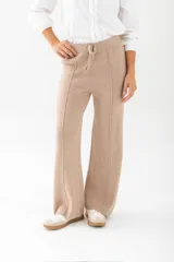 Pantalón de punto color beige, de corte palazzo y cintura con cordón ajustable.