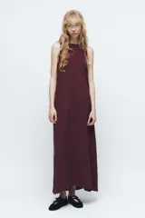 Vestido midi negro de cuello redondo y sin mangas. Corte amplio y fluido, con bolsillos laterales ocultos y cierre trasero con cremallera invisible.