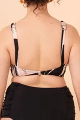 Top de bikini con estampado abstracto en blanco y negro, con breteles regulables, nudo central y broche en la espalda.