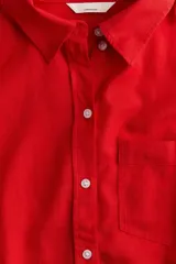 Camisa roja de lino con cuello clásico, botones frontales y bolsillo en el pecho.