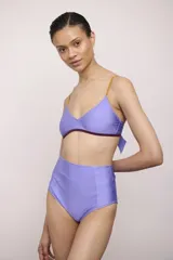Traje de baño de dos piezas color lila, compuesto por un corpiño triangular con breteles finos color mostaza y contorno inferior color borgoña, y una bombacha de tiro alto.