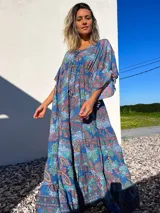 Vestido túnica largo de algodón con estampado de arabescos en tonos azules, rojos y verdes. Tiene escote en V con cordones y mangas acampanadas.