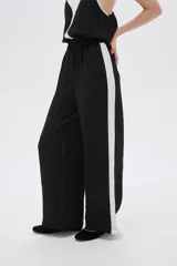 Pantalón ancho de poliéster color verde oliva con cintura elástica y una franja vertical blanca a cada lado.
