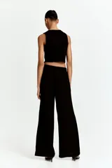 Pantalón negro de piernas anchas con bolsillos laterales, cintura elástica y cordón de ajuste con cuentas decorativas en los extremos.
