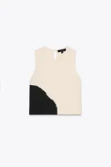 Top de punto color crema con diseño color block negro en la parte inferior. Tiene cuello redondo y sisa.