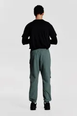 Pantalón jogger deportivo color verde grisáceo, con cintura elástica ajustable con cordón, bolsillos laterales con cierre, bolsillos cargo con solapa y bajos elásticos.