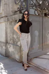 Jean gris lavado, estilo mom fit, con aplique fruncido en forma de espiral en la pierna izquierda, tiro alto, bolsillos delanteros y traseros funcionales, y cierre frontal con botón y cremallera.