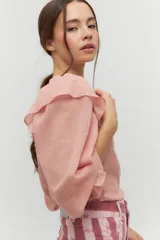 Blusa color rosa pálido de algodón con mangas cortas abullonadas y volados en el escote.