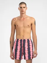 Short de baño para hombre con estampado de flores rosas sobre fondo gris, calce relajado, cintura elástica con cordón regulable, bolsillos laterales y bolsillo trasero con cierre. Incluye suspensor de malla fina hipoalergénico.
