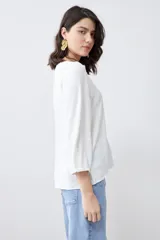 Blusa color crudo con escote en V y mangas largas.