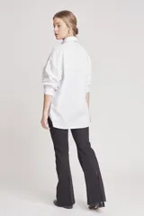 Camisa blanca de corte holgado con detalles de encaje en el frente y en las mangas.