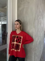Remera roja de manga larga con cuello en V y estampado frontal con recuadros de animal print en dorado.
