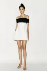 Minivestido blanco con escote recto palabra de honor con banda superior negra fruncida, corte ajustado y cierre lateral con cremallera oculta.