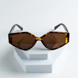 Lentes de sol con montura geométrica carey y lentes marrones. El logo de la marca está impreso en la patilla.