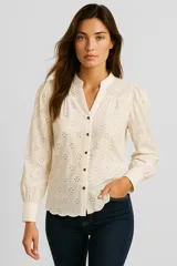 Blusa color crema con bordado inglés, cuello mao, mangas largas abullonadas y cierre frontal con botones.