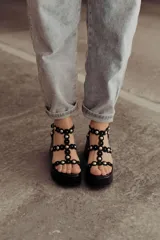 Sandalias negras de plataforma con tiras de gamuza y esferas doradas decorativas.