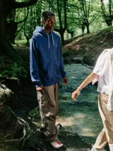 Canguro con cierre completo, color azul, con capucha y cordones trenzados blancos y negros. Presenta un pequeño logo bordado en el pecho izquierdo.