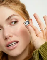 Anillo plateado con un cristal facetado gris en forma de lágrima.