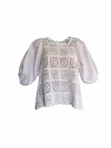 Blusa blanca con cuerpo de encaje de crochet cuadrillé y mangas abuchonadas de lino.
