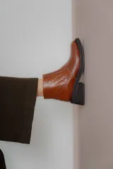 Bota corta color marrón con textura símil cuero de cocodrilo, caña baja, punta redondeada y taco cuadrado.