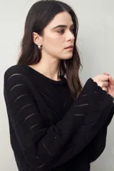 Sweater negro calado con diseño de líneas diagonales en relieve y mangas acampanadas.