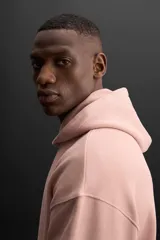 Sudadera con capucha color rosa viejo, confeccionada en tejido de algodón. Tiene cuello con capucha ajustable, manga larga, bolsillo tipo canguro y logo bordado en el pecho.