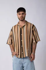 Camisa de manga corta con cuello clásico y botones frontales. Diseño con rayas verticales en tonos marrón, beige y negro.