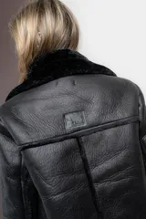 Gamulan negro de ecocuero con interior de símil piel, cuello solapa y cierre lateral con cremallera.