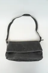 Bandolera negra con correa de hombro ajustable, solapa con cierre magnético y costuras en contraste.