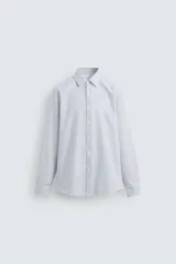 Camisa de hombre regular fit confeccionada en tejido de algodón a rayas verticales azules y blancas. Cuello italiano, manga larga con puños abotonados y cierre frontal con botones.