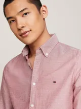 Camisa Tommy Hilfiger de corte slim fit, confeccionada en algodón Oxford con textura dobby. Diseño liso color salmón, con cuello abotonado, mangas largas con puños redondeados y logo bordado en el pecho.