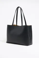 Bolso shopper negro de cuero con textura granulada, doble asa de hombro y logo blanco estampado en la parte inferior. Interior color caramelo con bolsillo con cierre. Cierre superior con lazo de cuero.