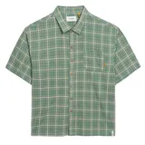 Camisa de manga corta con cuello camisero, confeccionada en tejido a cuadros (tartan) verde y beige. Presenta un bolsillo de parche en el pecho izquierdo y botones marrones.