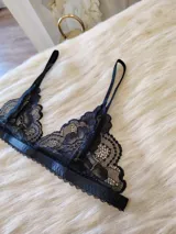Conjunto de lencería negro de encaje, compuesto por un bralette con breteles regulables y una tanga regulable con corte cola less y entrepierna de algodón.