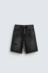 Bermuda de jean negro con corte amplio, cinco bolsillos, roturas y cierre con cremallera y botón.