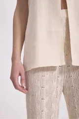 Pantalón de punto color crema, de corte acampanado y cintura alta.