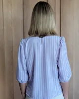 Remera blanca de algodón con mangas 3/4 abullonadas y cuello redondo. Presenta costuras a contratono en ruedo y cuello.