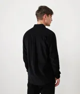 Camisa de hombre de manga larga, color verde oscuro, confeccionada en terciopelo, con cuello clásico y dos bolsillos frontales con tapa y botón.