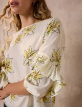 Blusa de gasa color crema con estampado de flores amarillas, de la marca Sioni. Tiene mangas 3/4 con volados y cuello redondo.