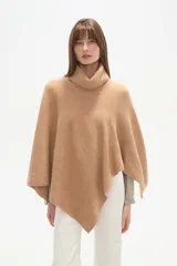 Poncho tejido color tostado, con cuello alto tipo tortuga y diseño asimétrico en el ruedo.
