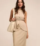 Conjunto color beige compuesto por una falda midi de lino y viscosa con lazo en la cintura y un chaleco sin mangas con botones. Incluye un bolso tote beige.