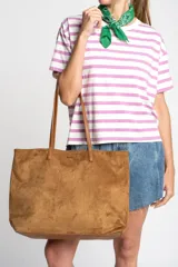 Bolso tipo tote de gamuza vegana color camel, con asas de mano y logo grabado en el frente.