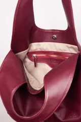 Bolso tote negro de cuero con manija circular rígida.