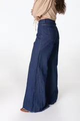 Pantalón de jean azul oscuro, de corte palazzo, con cintura alta y ruedo desflecado.