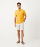 Polo de manga corta color amarillo, confeccionada en tejido de piqué con cuello clásico y tapeta de dos botones. Presenta ribetes blancos en cuello y mangas.
